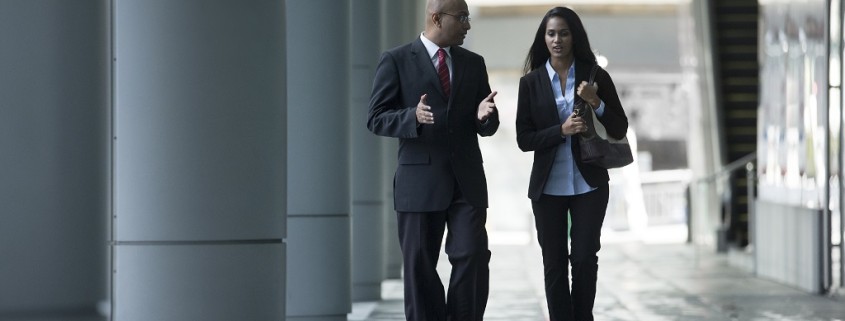 Happy Business colleagues walking outside office & talking to each other.