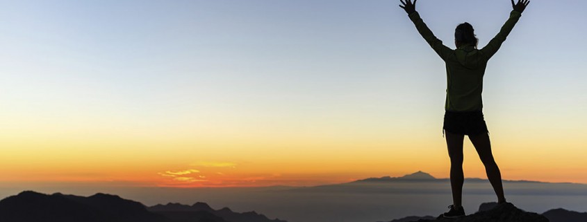 Woman successful hiking climbing silhouette in mountains, motivation and inspiration in beautiful sunset and ocean. Female hiker with arms up outstretched on mountain top looking at beautiful night sunset inspirational landscape.